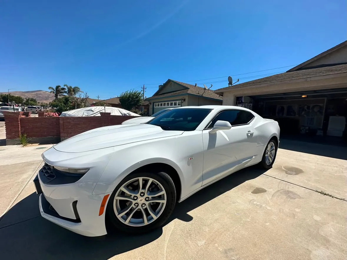 A white Chevrolet Camaro with film on the front door and rear quarter glass
