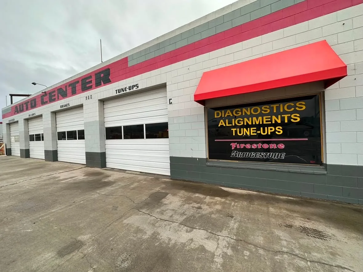 The front of an auto center with tinted windows and a red awning