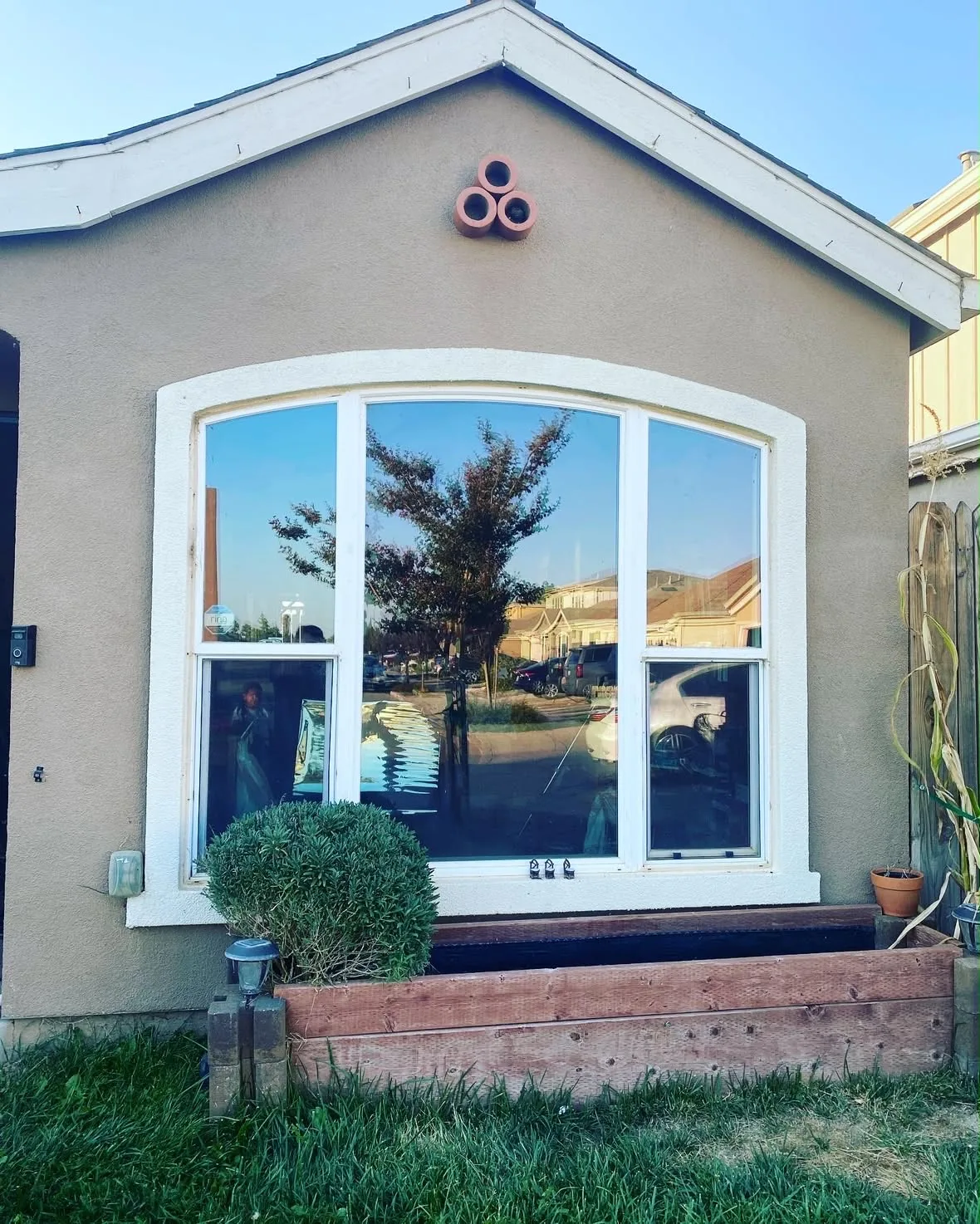 An arched bay window with residential window film reflecting the street