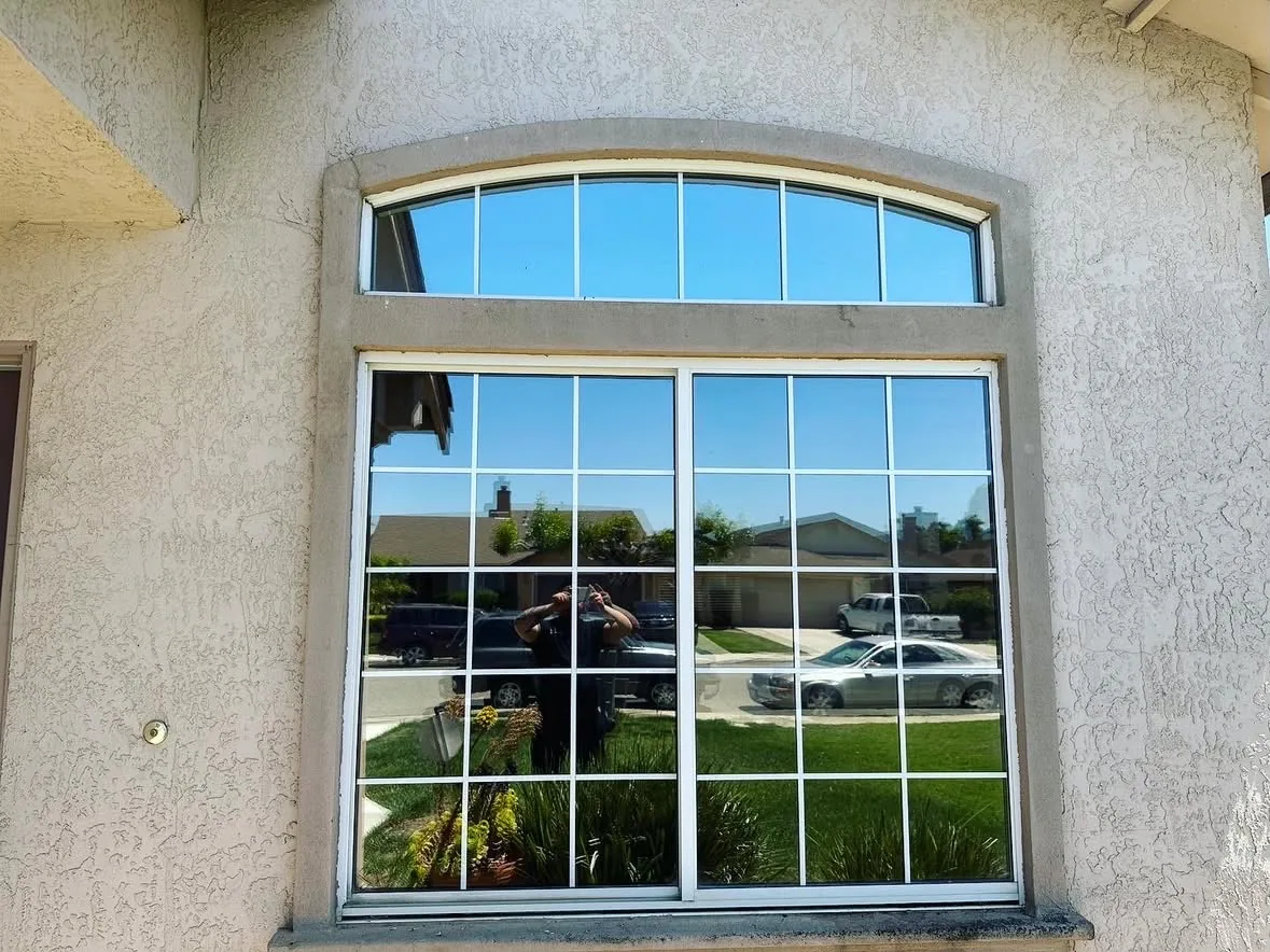 A large arched grid window on a stucco home after residential film